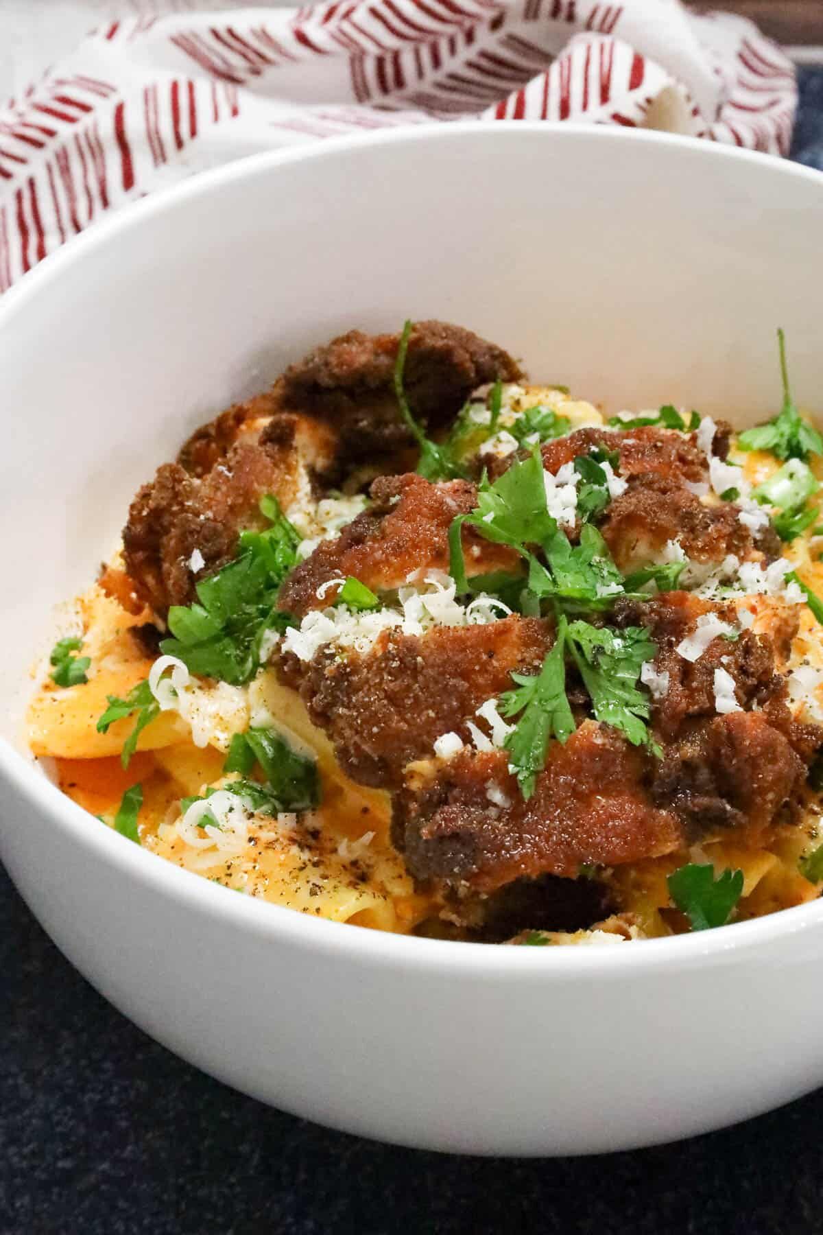 gochujang pasta topped with chicken breast and topped with fresh herbs