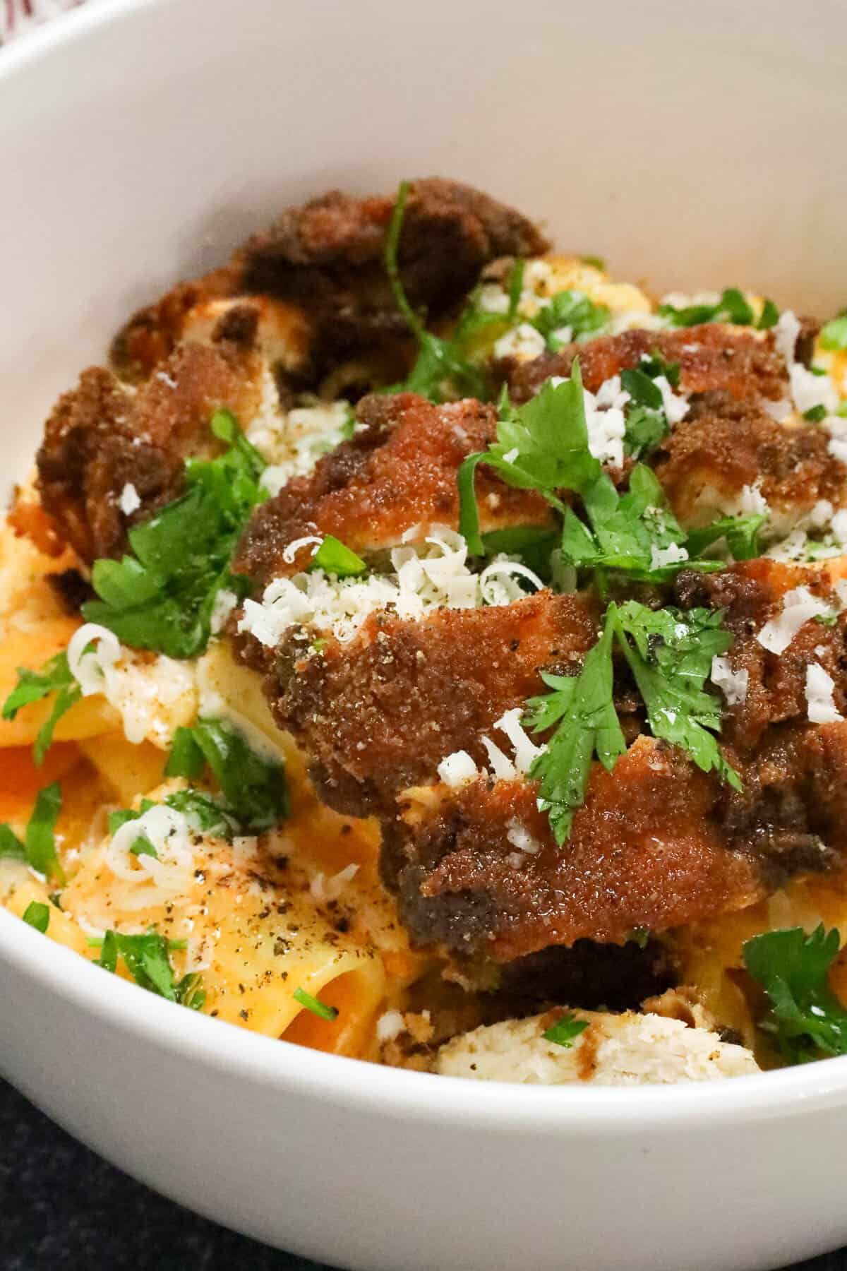 gochujang pasta topped with chicken breast and topped with fresh herbs