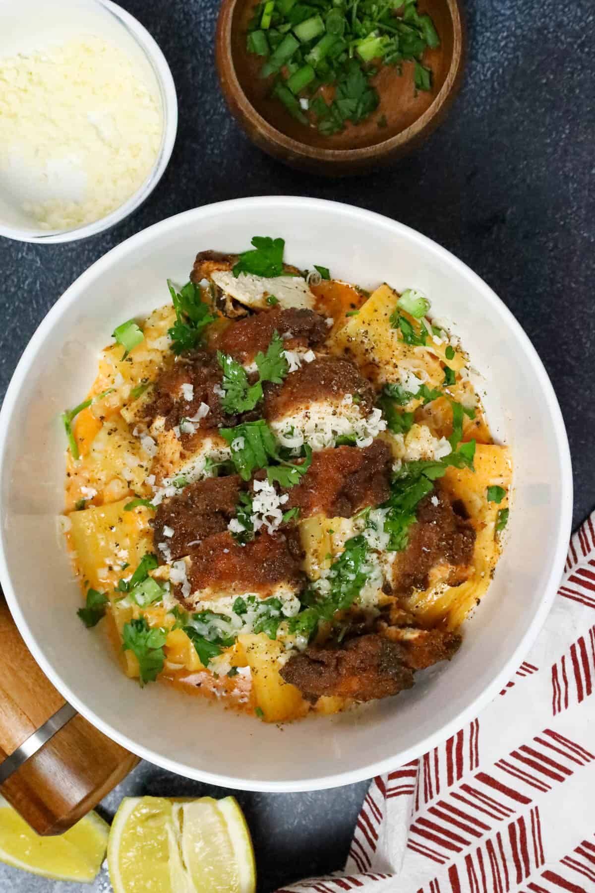 gochujang pasta topped with chicken breast and topped with fresh herbs